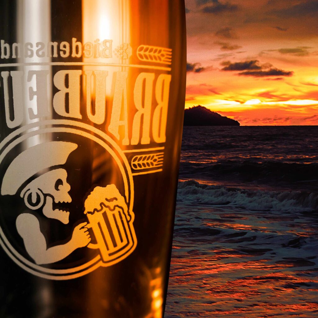 Breubeuter-Logo auf einem Willy-Becher angestrahlt vom Sonnenuntergang am Meer
